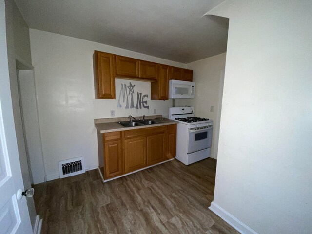 kitchen featuring dark wood-type flooring, sink, and white appliances