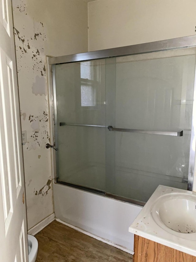 full bathroom with toilet, combined bath / shower with glass door, wood-type flooring, and vanity