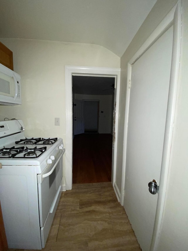 kitchen featuring lofted ceiling and white appliances