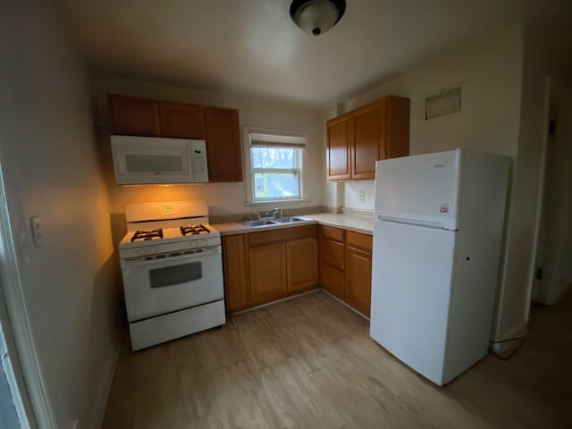 kitchen featuring sink, white appliances, and light hardwood / wood-style floors