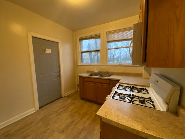 kitchen with sink, white gas stove, and light wood-type flooring