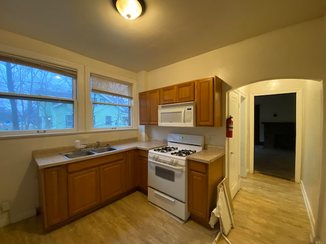 kitchen with sink, white appliances, and light hardwood / wood-style flooring