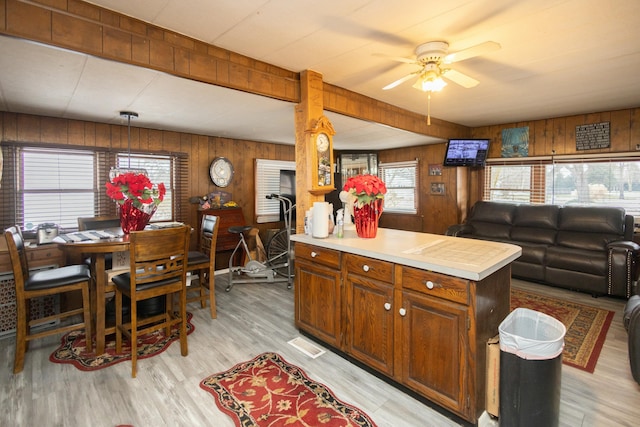 kitchen featuring ceiling fan, plenty of natural light, light hardwood / wood-style floors, and wooden walls