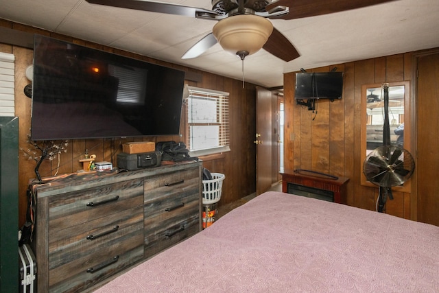 bedroom with ceiling fan and wood walls