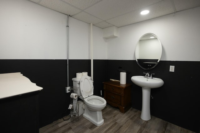 bathroom with hardwood / wood-style floors, toilet, and a drop ceiling