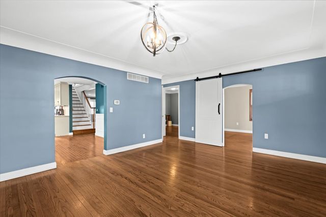 spare room featuring a notable chandelier, a barn door, and dark wood-type flooring