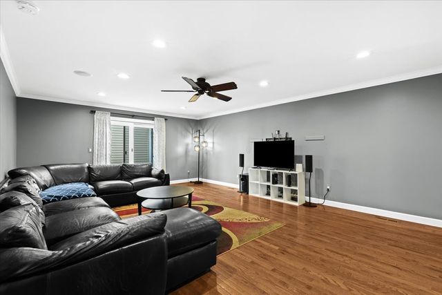 living room featuring hardwood / wood-style flooring, ceiling fan, and crown molding