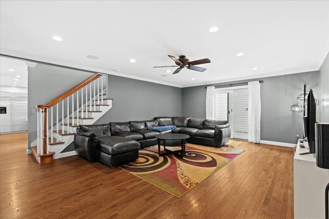 living room featuring hardwood / wood-style flooring, ceiling fan, and ornamental molding