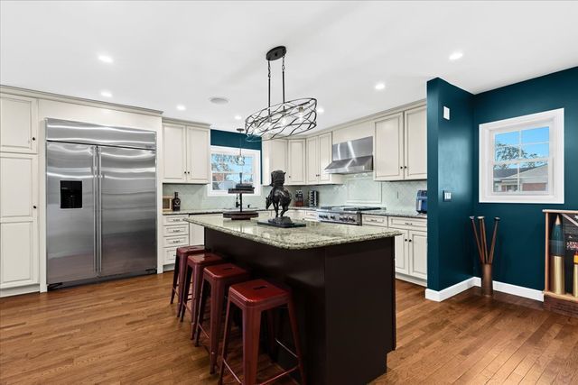 1807 Samoset Rd, Royal Oak, MI 48073 - kitchen featuring wall chimney range hood, backsplash, dark wood-style flooring, and built in fridge