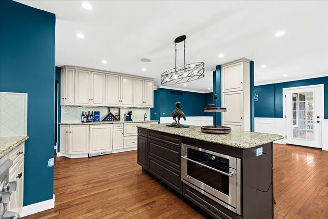 kitchen featuring pendant lighting, a center island, stainless steel oven, backsplash, and dark hardwood / wood-style flooring