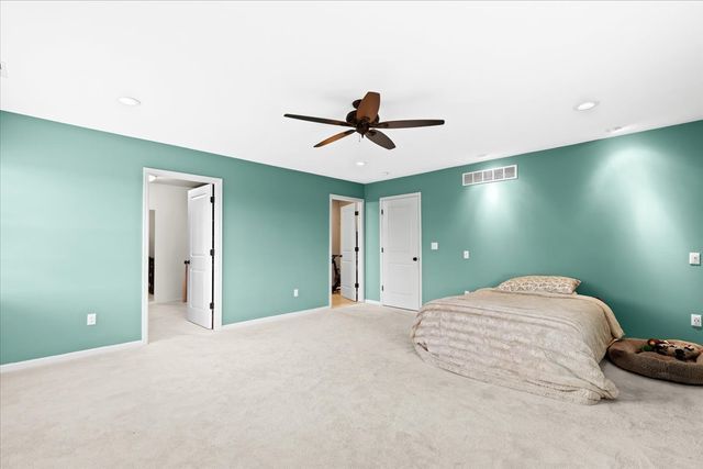 bedroom featuring light carpet, ensuite bath, and ceiling fan