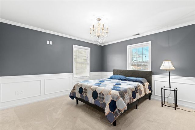 carpeted bedroom featuring an inviting chandelier and ornamental molding