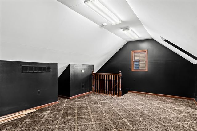 bonus room with dark carpet and lofted ceiling