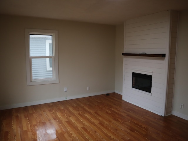 unfurnished living room featuring wood-type flooring and a large fireplace