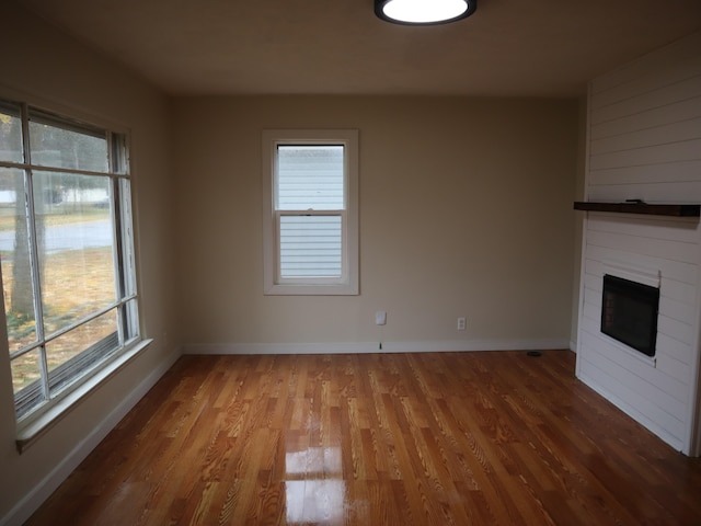 unfurnished living room with a large fireplace and hardwood / wood-style flooring