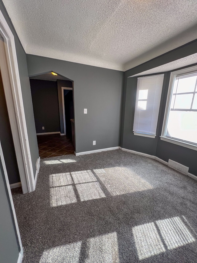 carpeted empty room with a textured ceiling