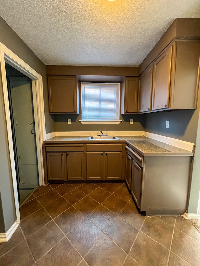 kitchen with a textured ceiling, dark tile patterned flooring, and sink