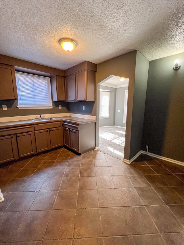 kitchen with dark tile patterned floors, a textured ceiling, and sink