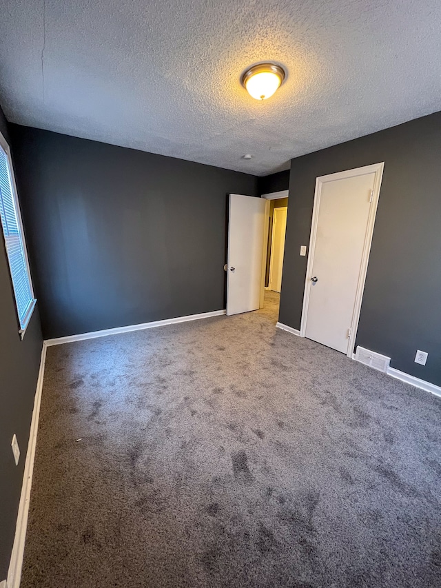 carpeted spare room featuring a textured ceiling