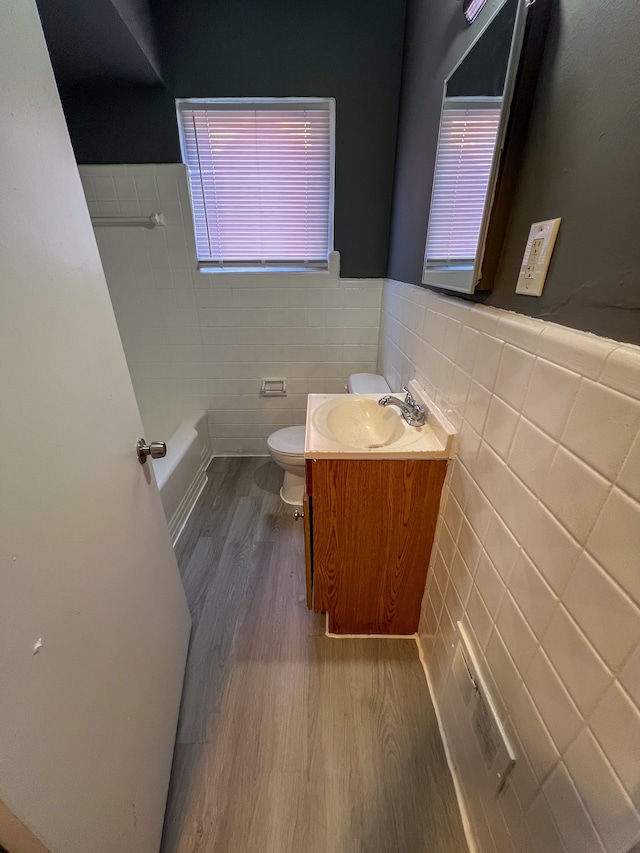 bathroom featuring vanity, toilet, wood-type flooring, and tile walls