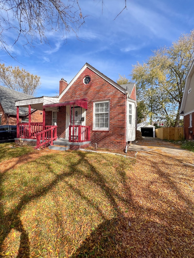 view of front of property featuring an outbuilding, a front lawn, and a porch