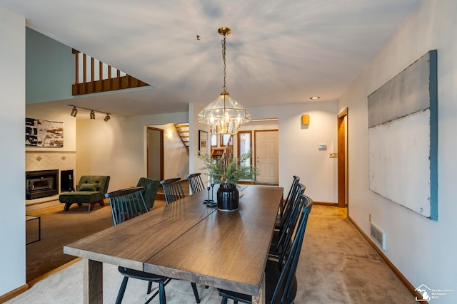 dining area with light carpet, rail lighting, and a chandelier