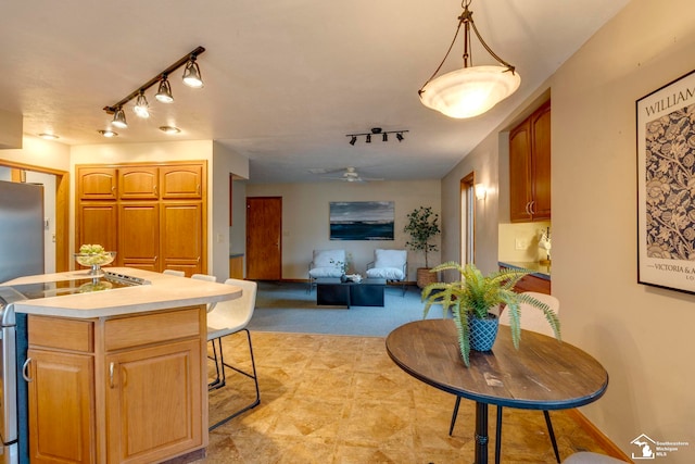 kitchen featuring ceiling fan, stainless steel range oven, track lighting, decorative light fixtures, and a center island with sink