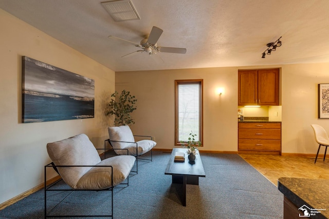 sitting room with light carpet, a textured ceiling, and ceiling fan