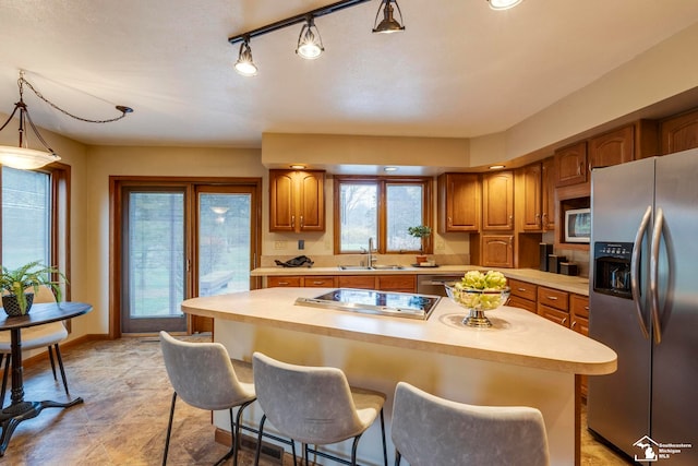 kitchen featuring a kitchen breakfast bar, sink, appliances with stainless steel finishes, decorative light fixtures, and a kitchen island