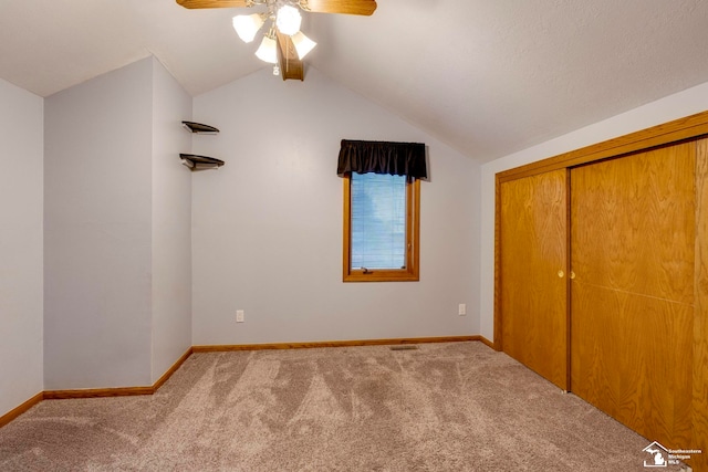 unfurnished bedroom with ceiling fan, a closet, light colored carpet, and lofted ceiling