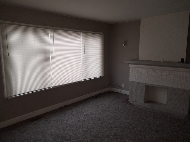 unfurnished living room with carpet flooring and a brick fireplace