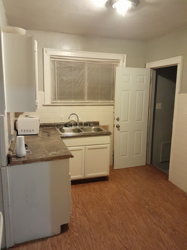 kitchen with tasteful backsplash, white cabinetry, sink, and hardwood / wood-style floors