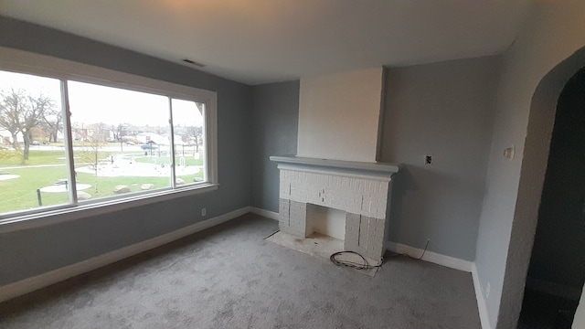 unfurnished living room with light colored carpet and a brick fireplace