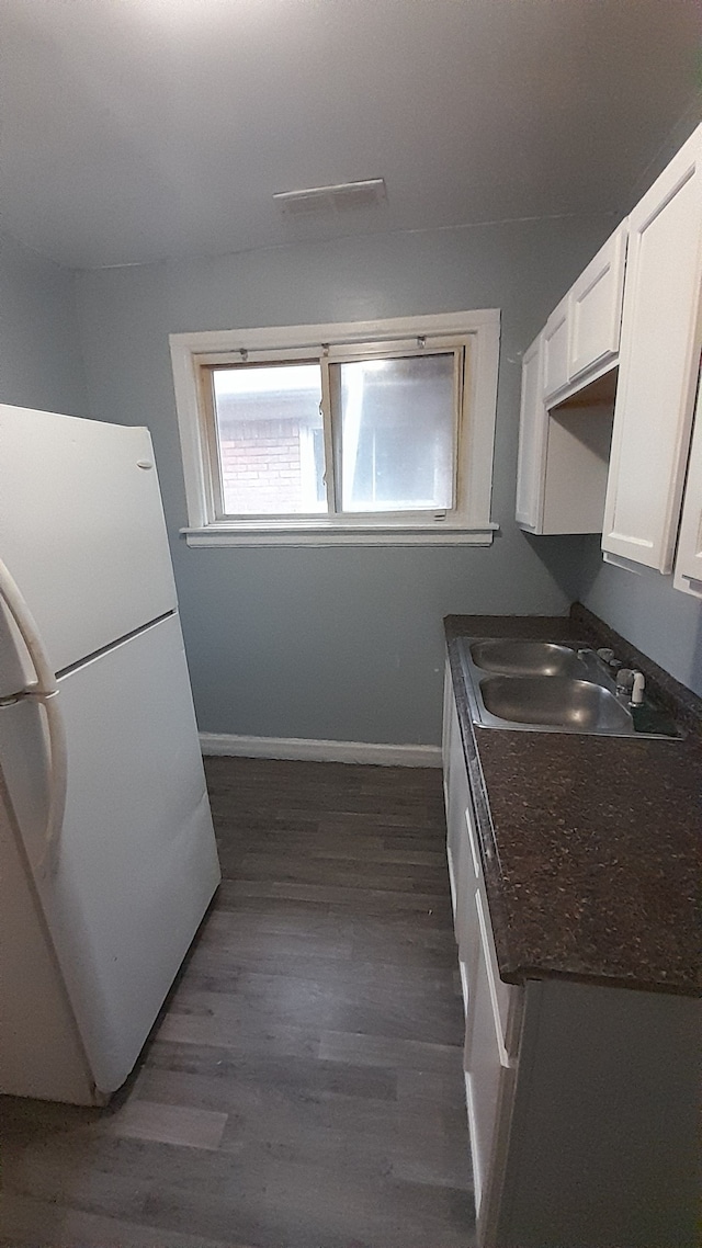 kitchen with dark stone counters, white refrigerator, sink, dark hardwood / wood-style floors, and white cabinetry