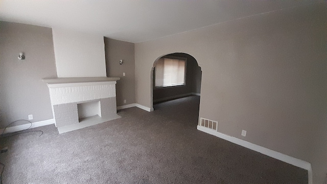 unfurnished living room featuring dark colored carpet and a fireplace