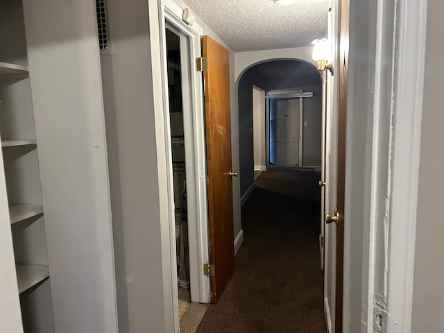 hall featuring carpet floors and a textured ceiling