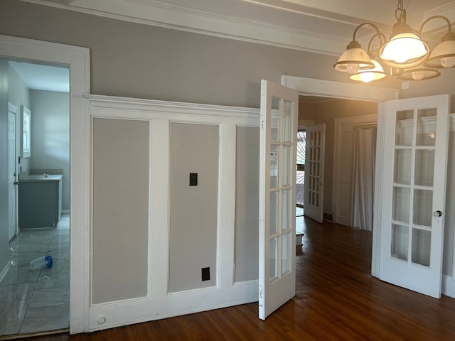 corridor featuring dark hardwood / wood-style floors, an inviting chandelier, crown molding, and french doors