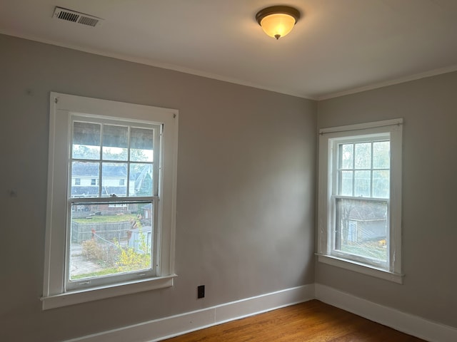 empty room featuring wood-type flooring and crown molding