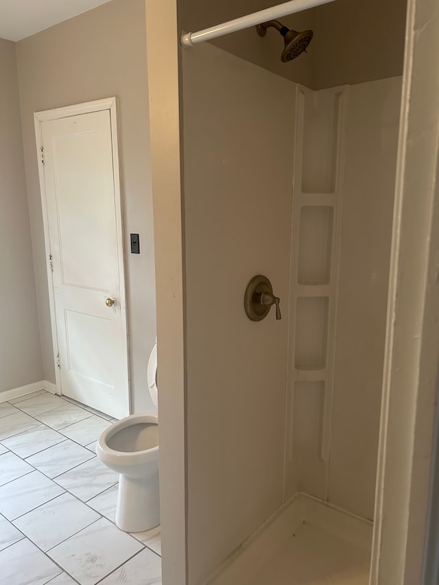 bathroom featuring tile patterned flooring, toilet, and a shower