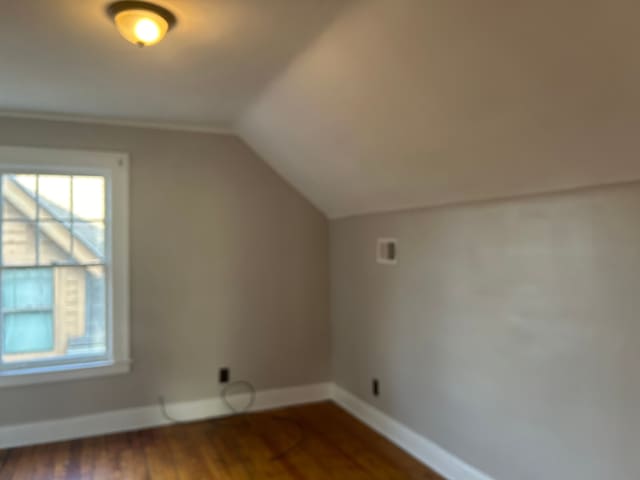 additional living space with dark hardwood / wood-style flooring and vaulted ceiling