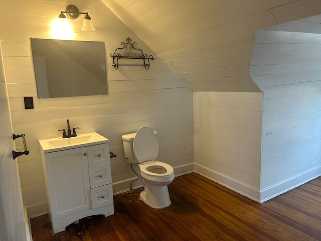 bathroom with toilet, hardwood / wood-style floors, vanity, and vaulted ceiling