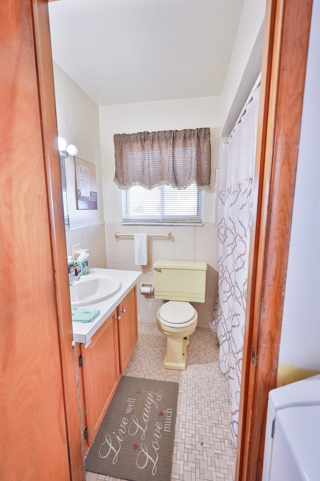 bathroom featuring tile patterned floors, vanity, toilet, and tile walls