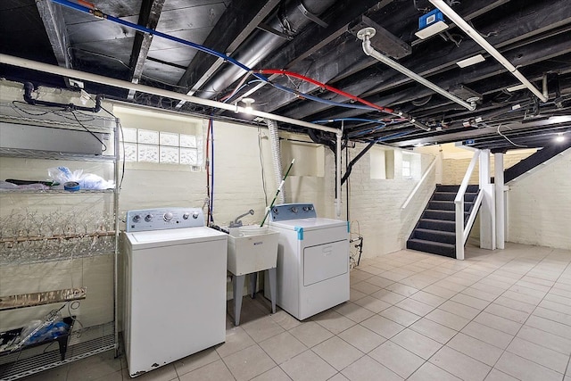 clothes washing area featuring light tile patterned floors, sink, and washing machine and clothes dryer