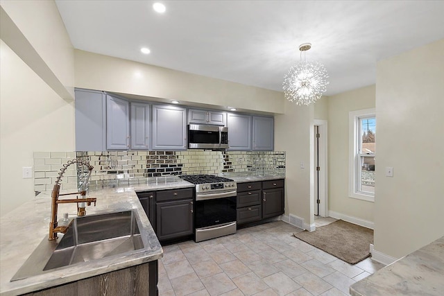 kitchen featuring gray cabinetry, stainless steel appliances, sink, a chandelier, and hanging light fixtures