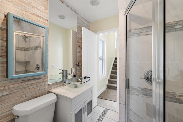 bathroom featuring tile patterned floors, toilet, wooden walls, vanity, and a shower with shower door