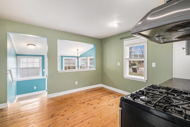 kitchen featuring light wood-type flooring, ventilation hood, a wealth of natural light, and black range with gas cooktop