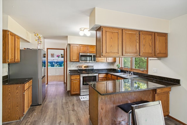 kitchen with kitchen peninsula, backsplash, stainless steel appliances, sink, and dark hardwood / wood-style floors