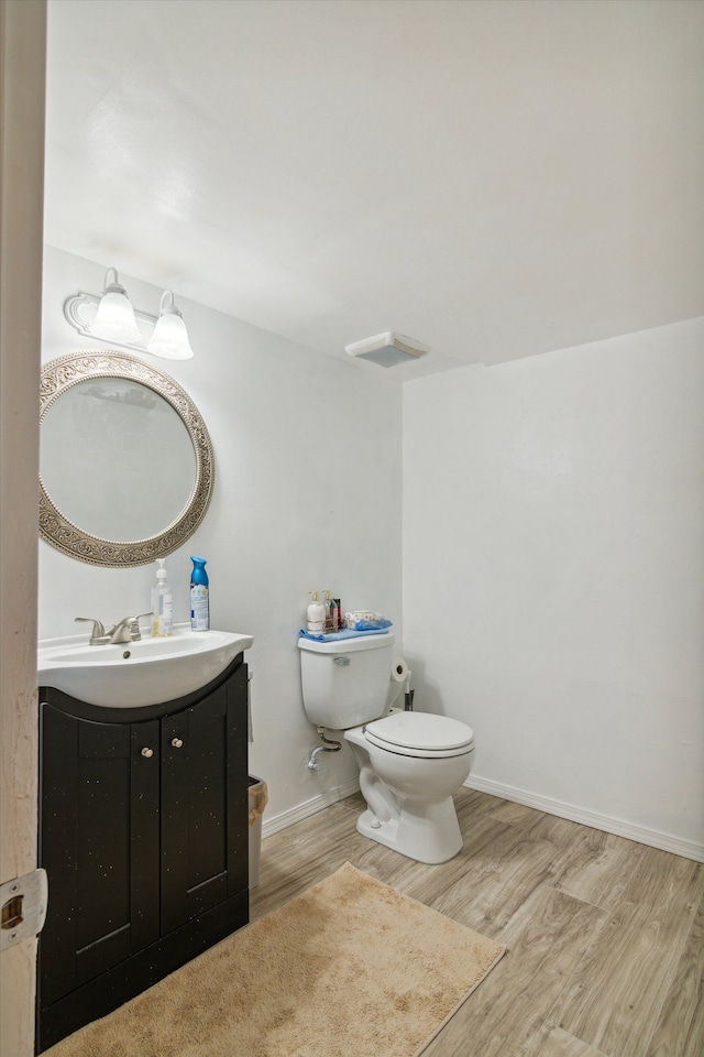 bathroom with wood-type flooring, vanity, and toilet