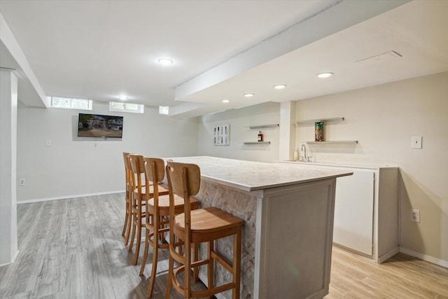 bar with light hardwood / wood-style flooring and sink