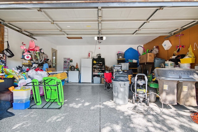 garage featuring white fridge and a garage door opener